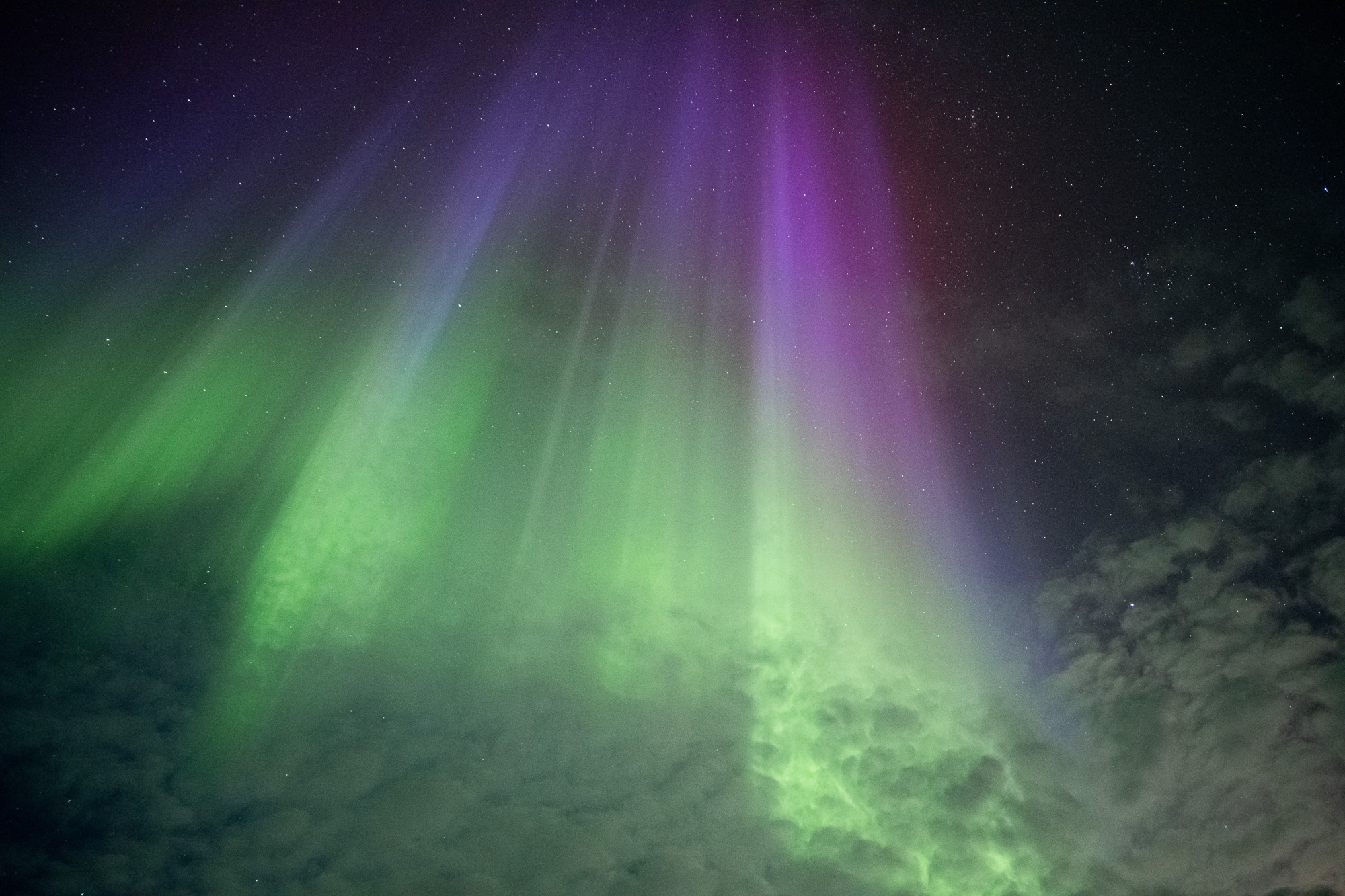 Aurora curtains through clouds in Alaska