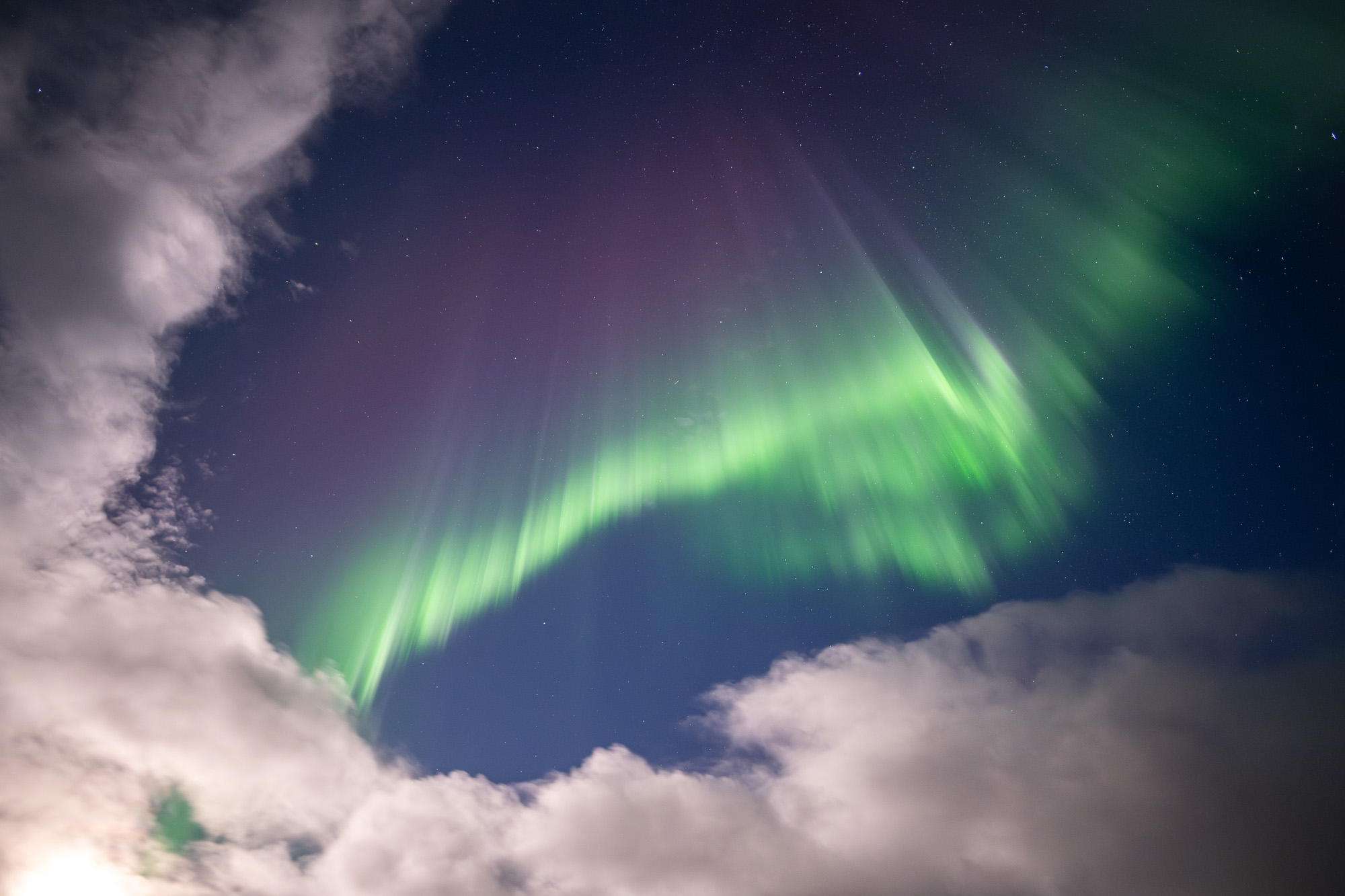 Aurora curtains through clouds in Alaska