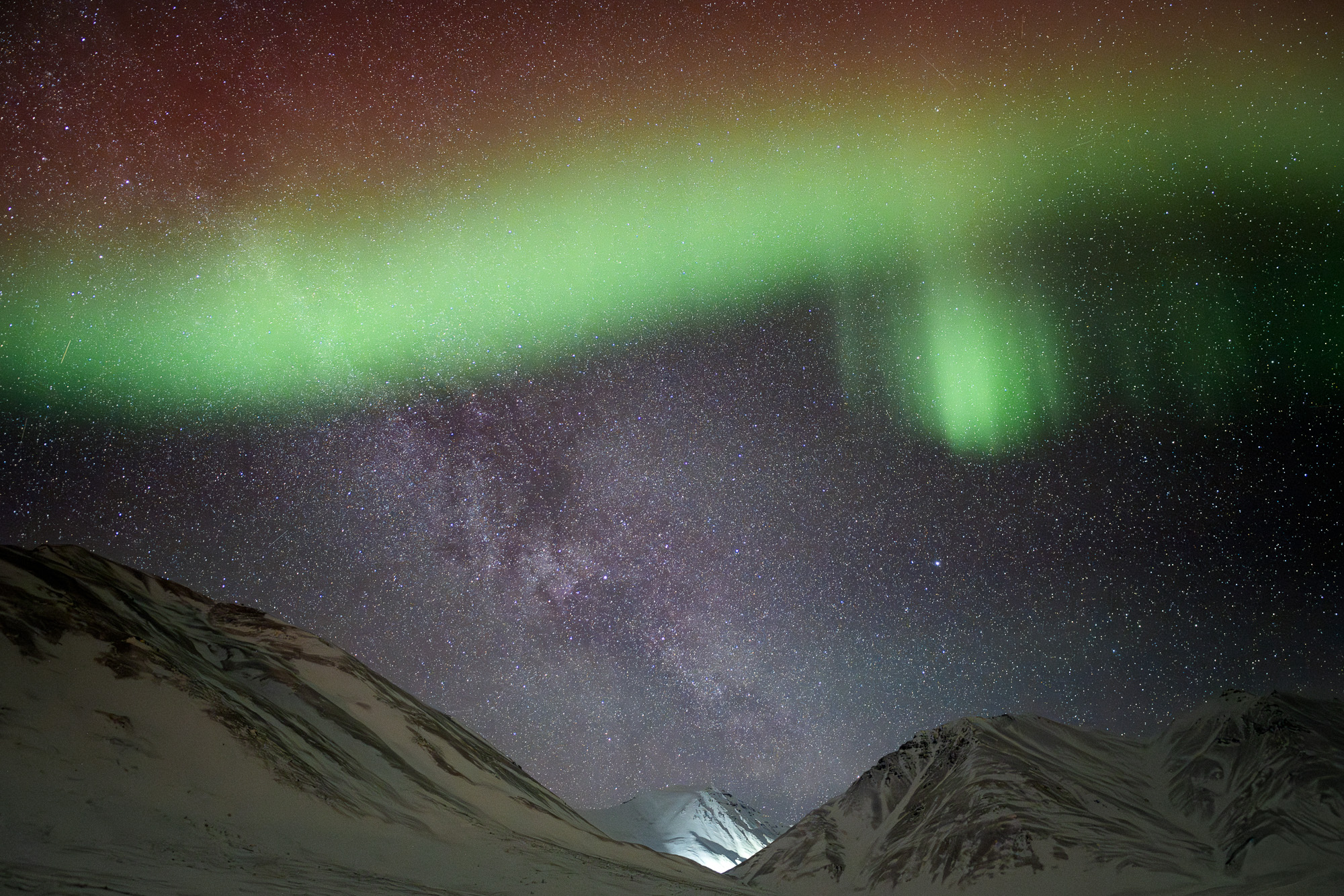Aurora and the Milky Way above mountains in Alaska